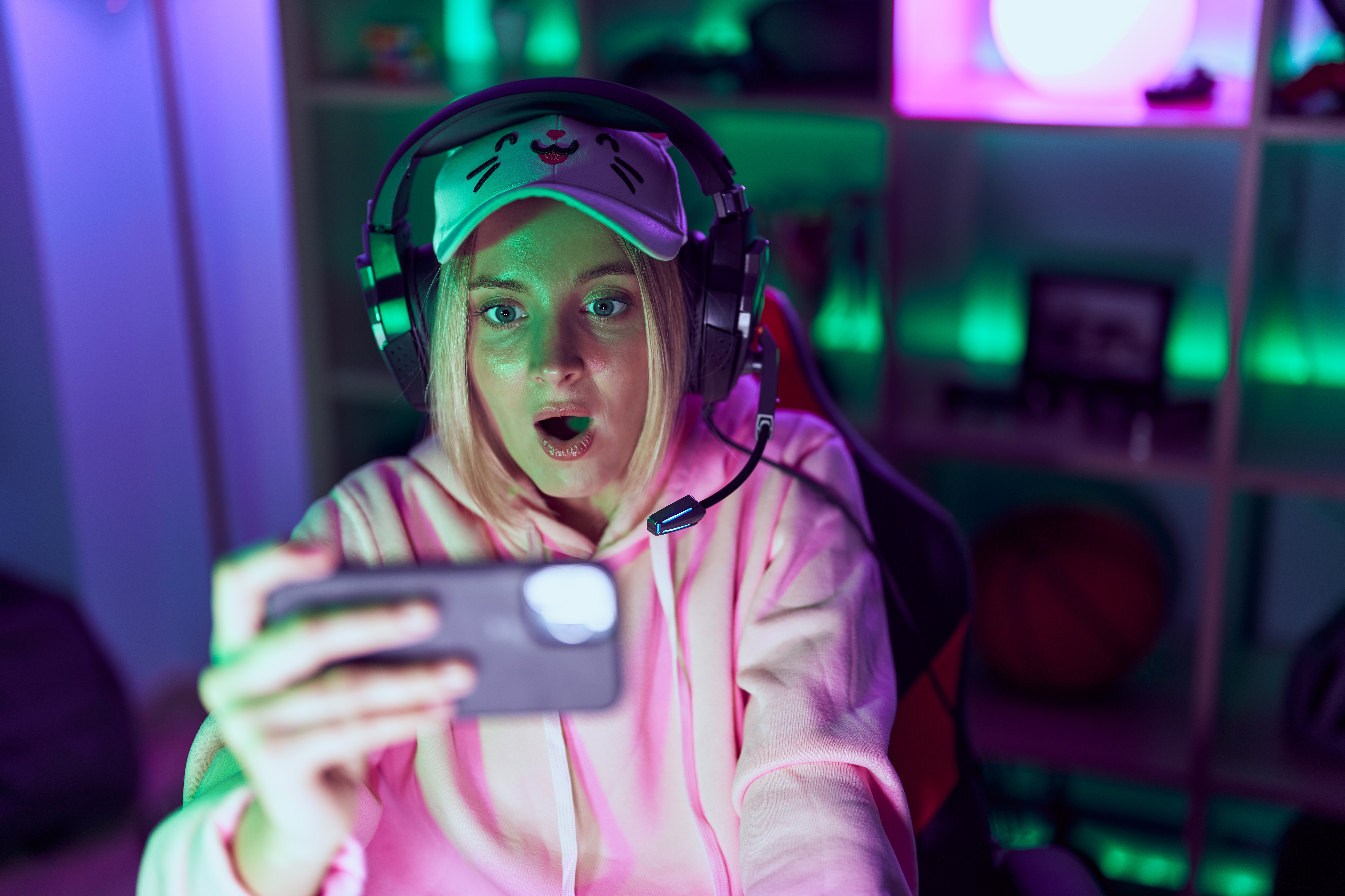 young-caucasian-woman-playing-video-games-with-smartphone-pointing-thumb-up-side-smiling-happy-with-open-mouth